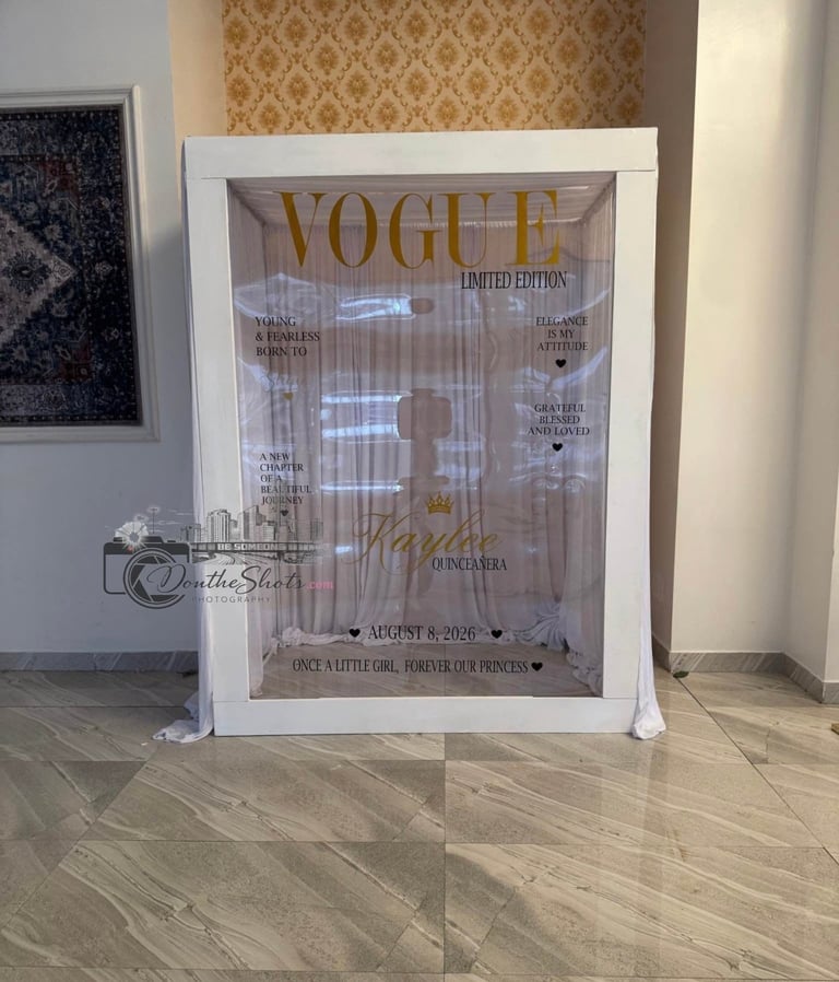 Framed Vogue magazine cover with white border displayed on wooden floor against patterned wallpaper