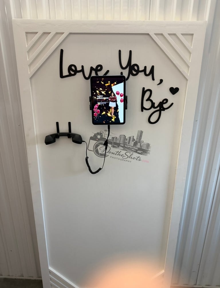 Wall art with handwritten love You, Be text, decorative phone holder, and cityscape sketch on white paneled wall