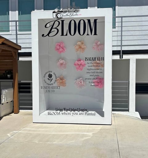 Large outdoor display sign for Bloom campaign featuring pink flowers and Isaiah 61:11 scripture quote