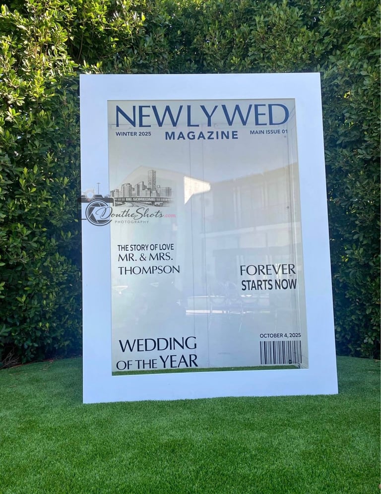 Oversized Newly Wed Magazine cover displayed on grass featuring wedding photo and Wedding of the Year headline