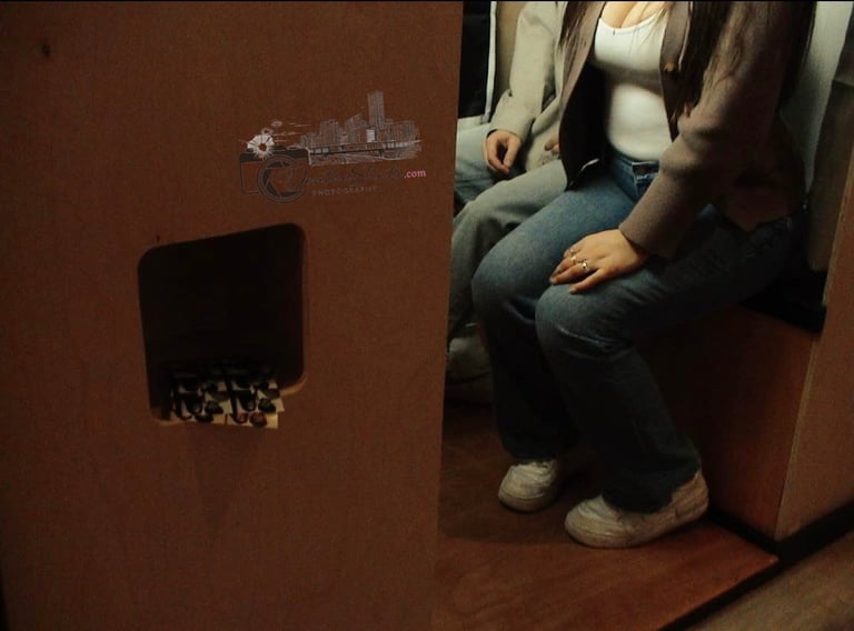 Person sitting on floor next to wall with black box cavity containing small objects and artwork displayed above