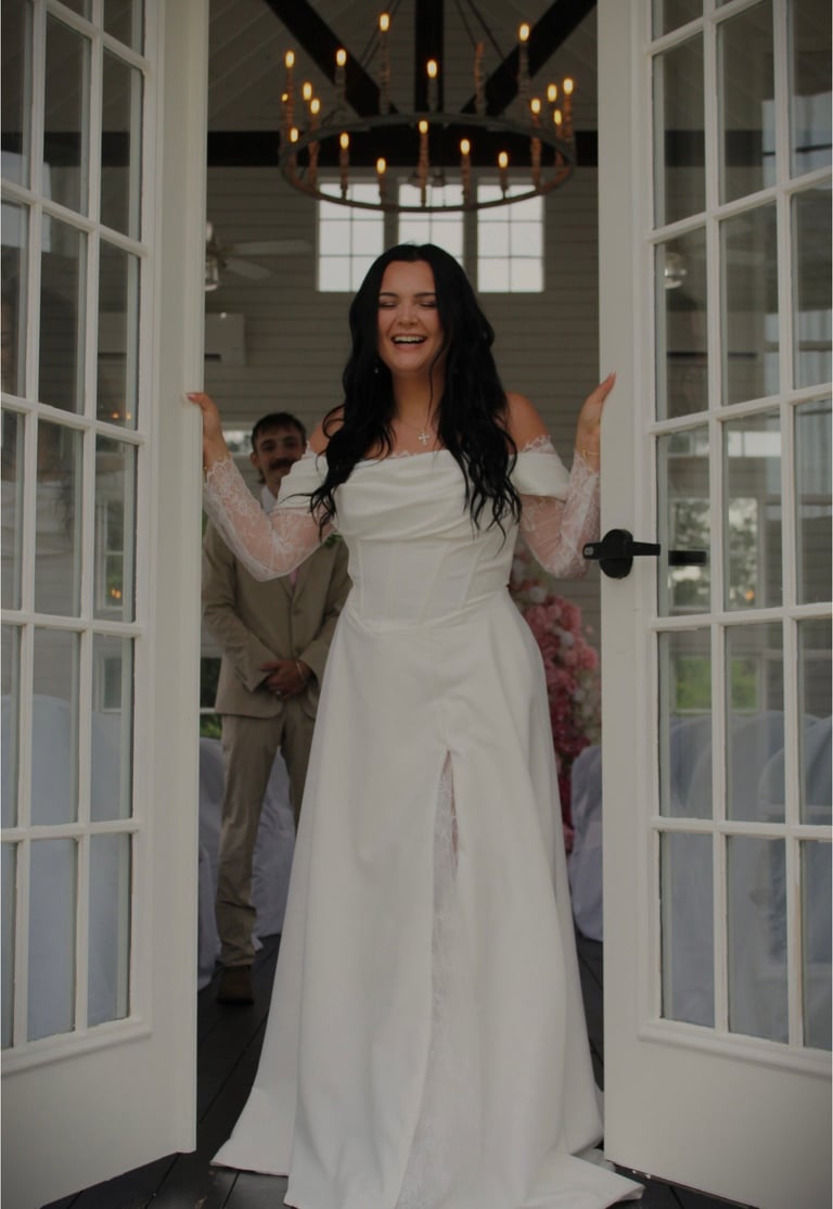 Woman in white off-shoulder wedding dress standing in doorway