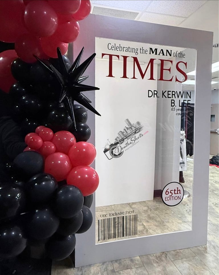 Large display poster for Celebrating the Man of the Times featuring Dr. Kerwin B. Lee, decorated with red and black balloons