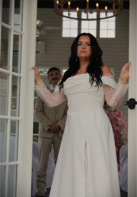 Bride in white off-shoulder lace wedding dress standing in doorway