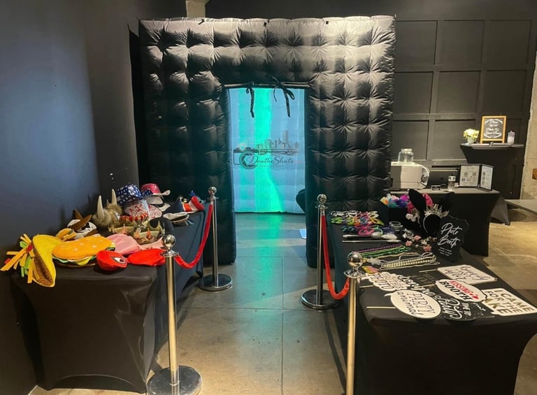 Museum display with colorful artifacts on black tables flanking a turquoise-lit neon doorway entrance