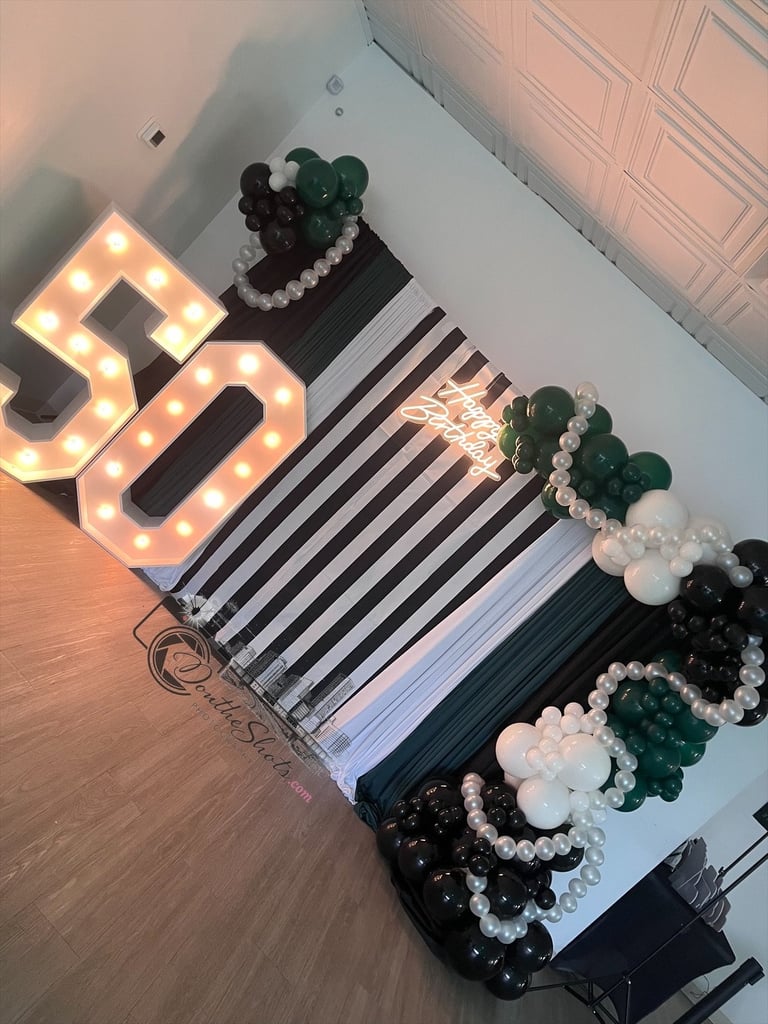 Illuminated 50 sign with green and white balloons and pearl garlands