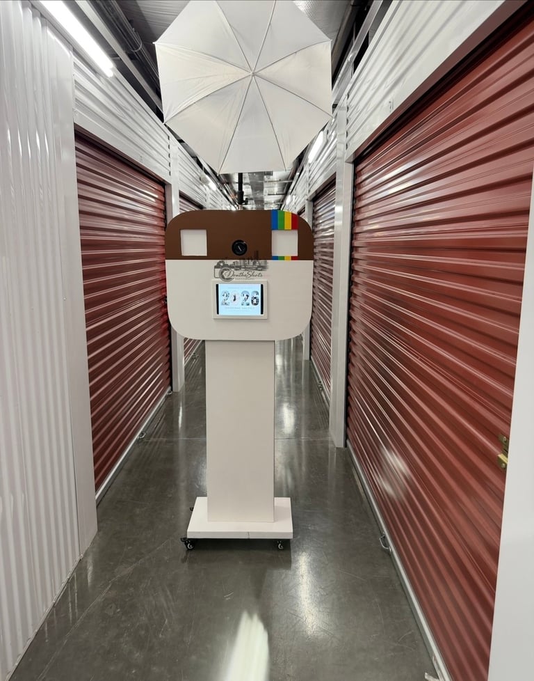 Self-service kiosk in a narrow storage unit hallway with red metal doors on both sides and white umbrella overhead