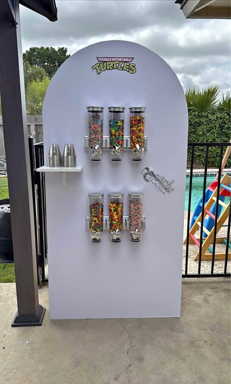Custom Teenage Mutant Ninja Turtles shaped candy dispenser kiosk with colorful cereal in glass tubes in a poolside setting