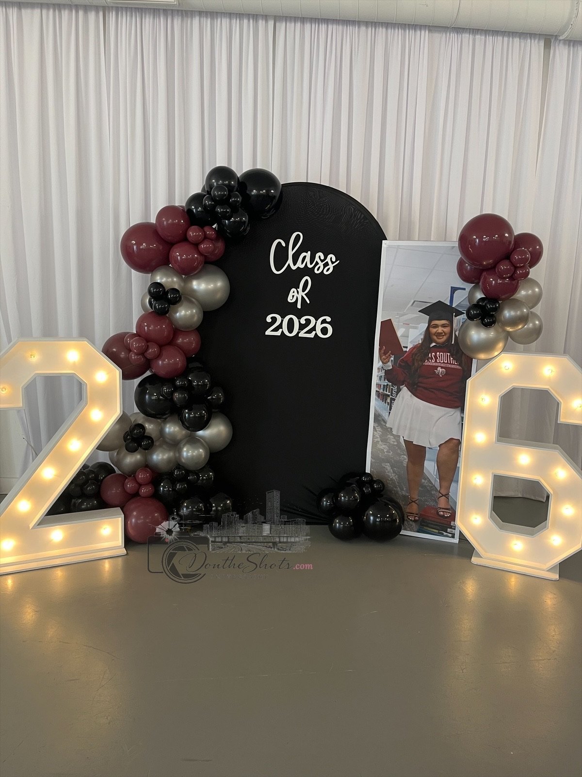 Class of 2026 graduation decorations with illuminated numbers, burgundy and black balloons, and student photo display