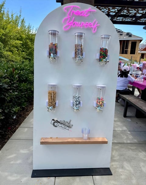 White floral arrangement display stand with neon pink Shear Yourself sign and six glass tubes containing decorative flowers and greenery