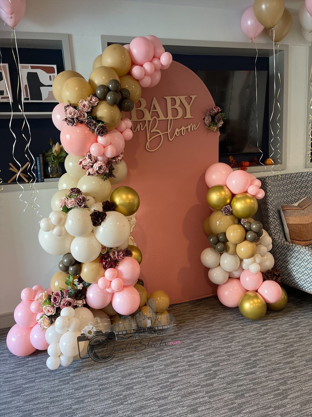 Baby shower backdrop with Baby in Bloom sign and pink, gold, white, and burgundy balloon garlands