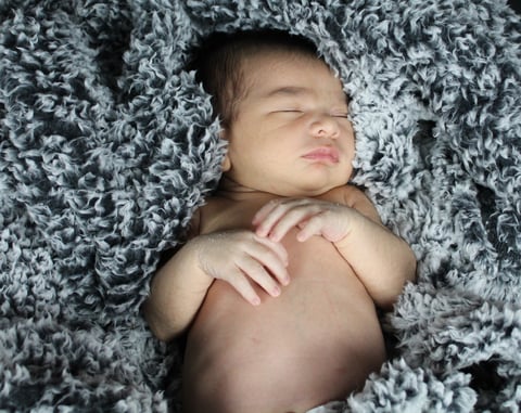 Newborn baby sleeping peacefully on a gray textured blanket