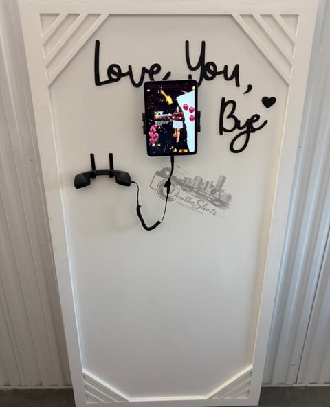 White decorative wall panel with Love You, Be handwritten text, featuring a small photo, decorative cord with clips, and a cityscape illustration